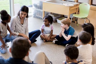 teacher sitting in circle time with young students