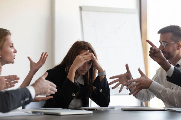 adults at table arguing one with head in hands