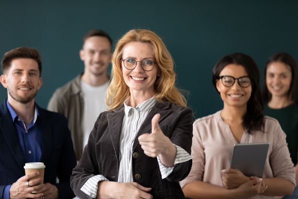 Administration or principal showing thumbs up hand gesture with teachers in background